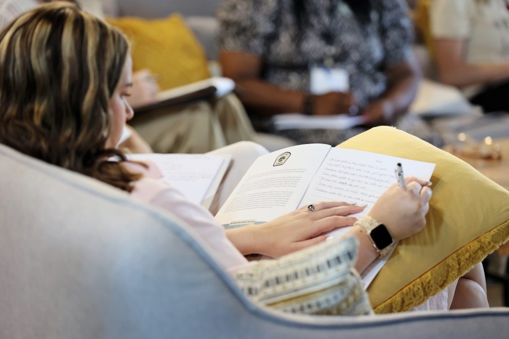 Girl sitting on couch writing in her notebook