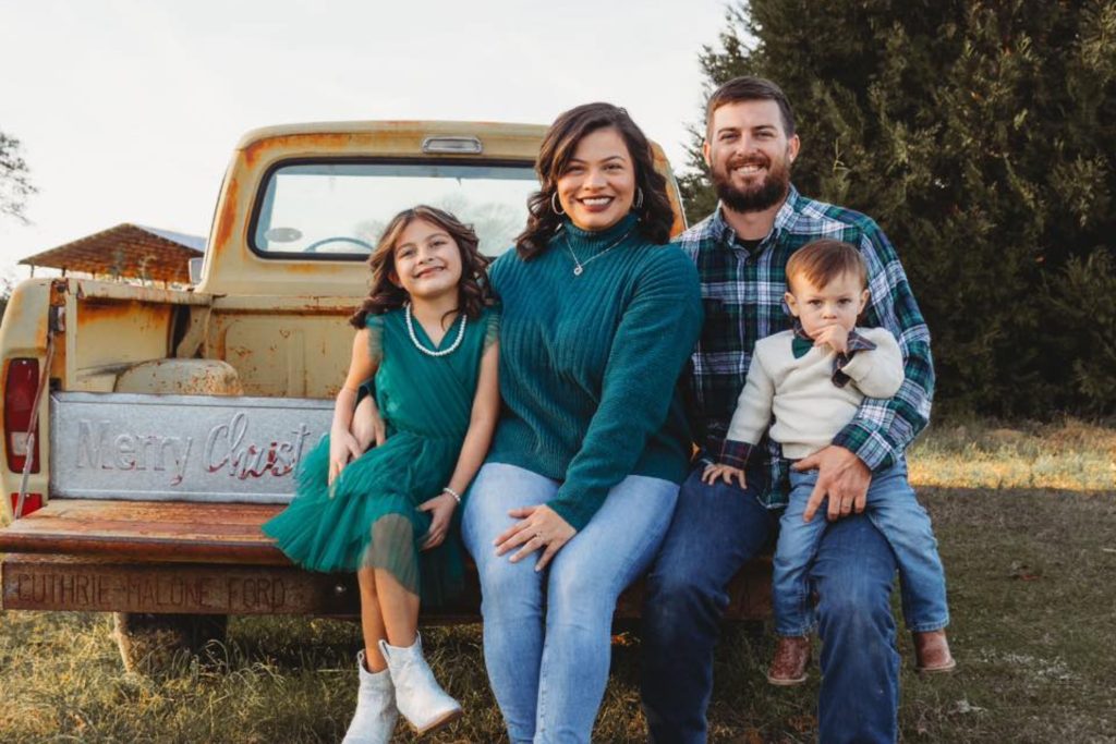Photo of family sitting on back of old, rusted pickup truck