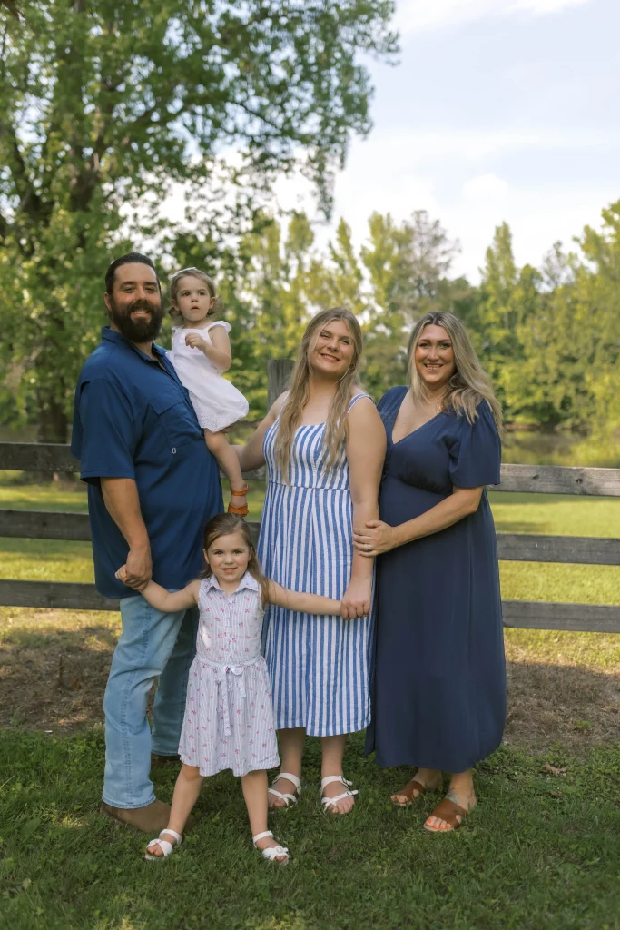 family picture of the Rowell family in front of wood fence and big tree