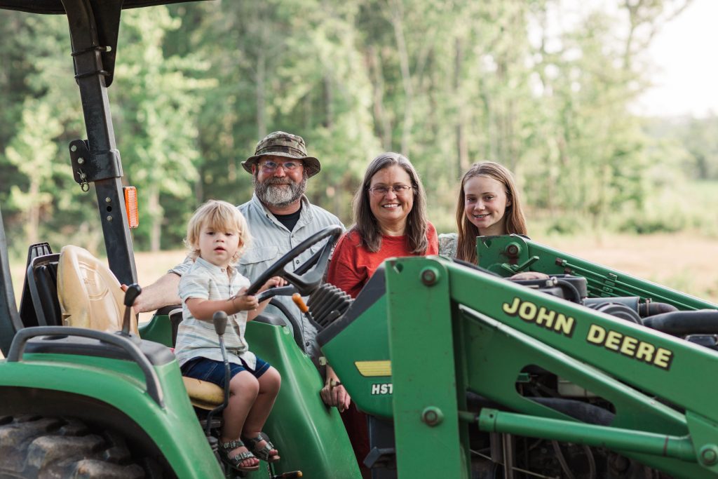 Photo of the Wells family sitting and standing around a John Deere tractor