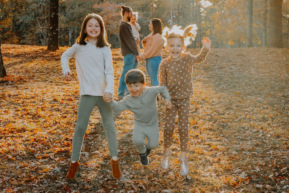 Family in an autumn woods setting taking family photos