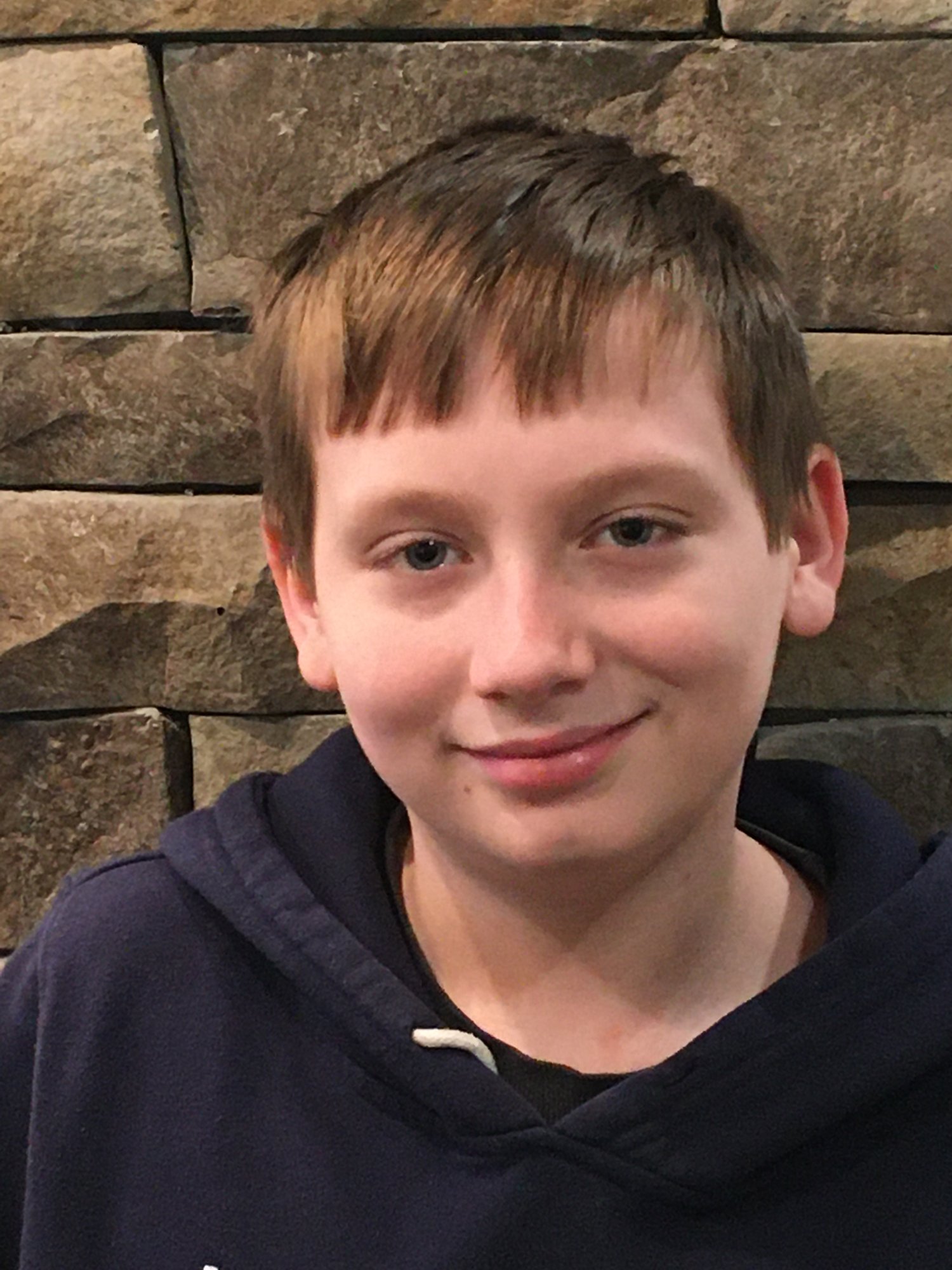 AJ at 11 years old, smiling in a close-up portrait.