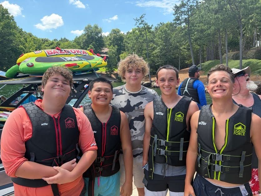 Five Boys' Ranch teens grin together, four of them wearing life jackets.