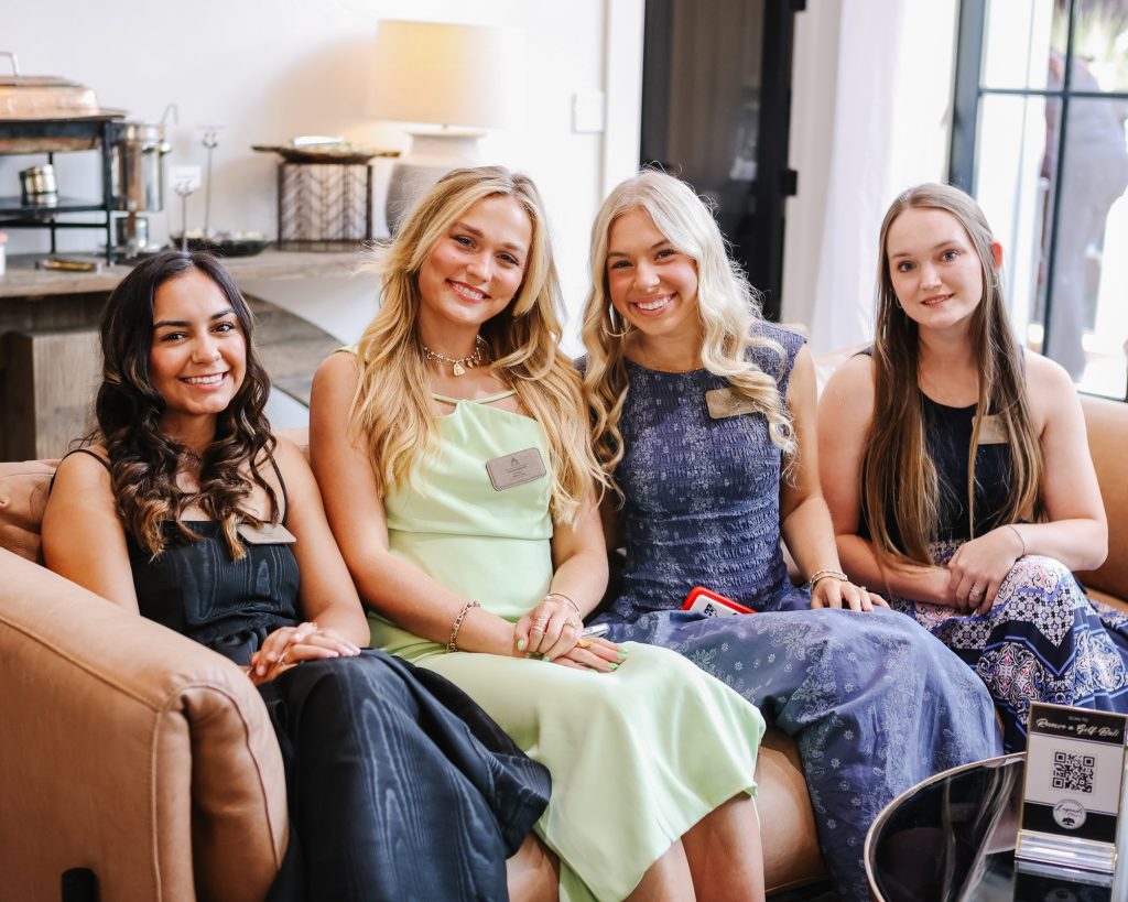 Taylor sits on a couch, smiling with three fellow ASCENDants.