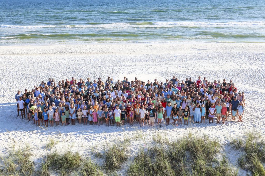 The Big Oak Ranch family gathers together for a group photo on a white-sand beach.