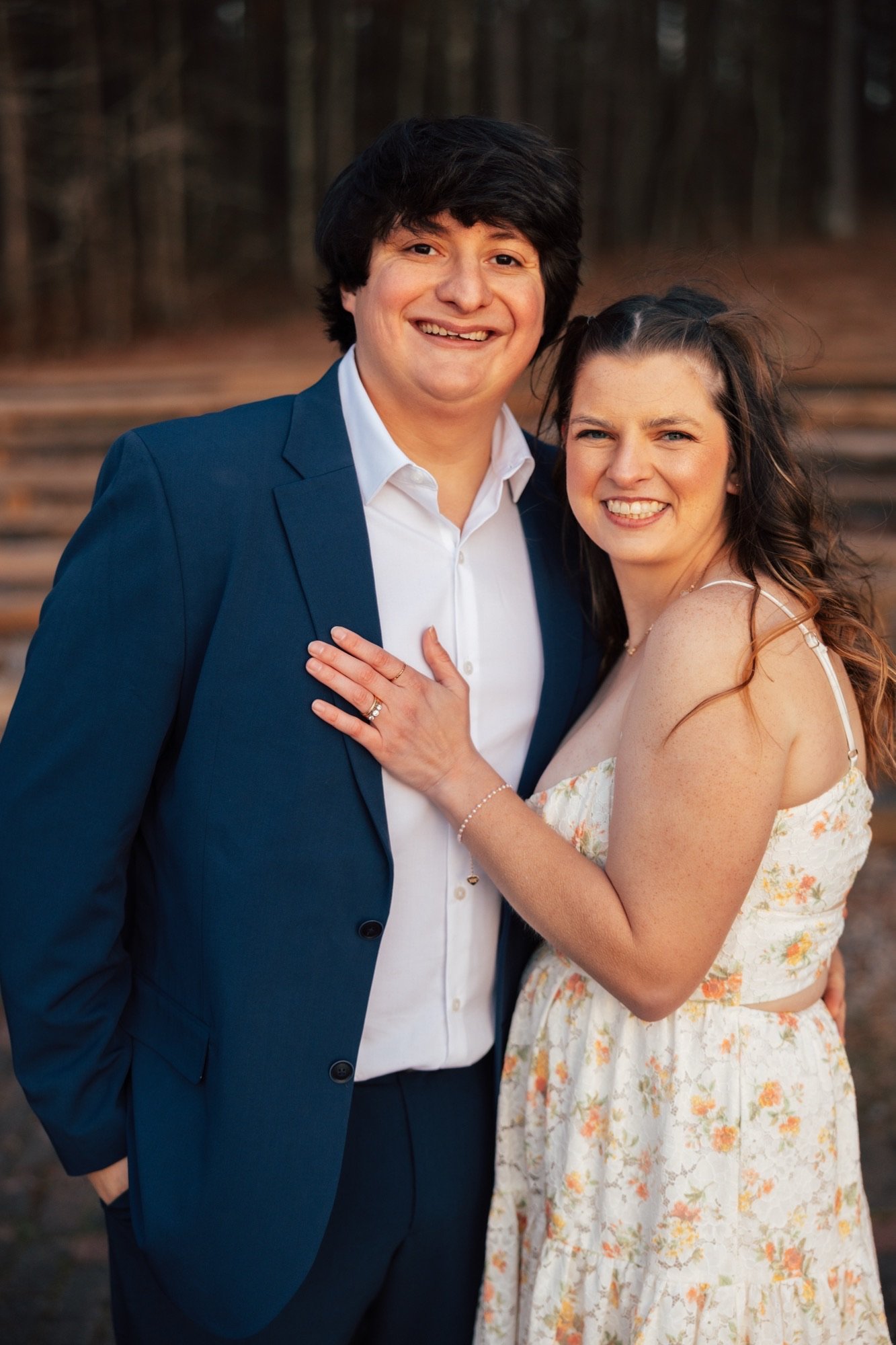 Gilbert and his fiancée, Kelsey, smile together outdoors, her hand resting on his chest.