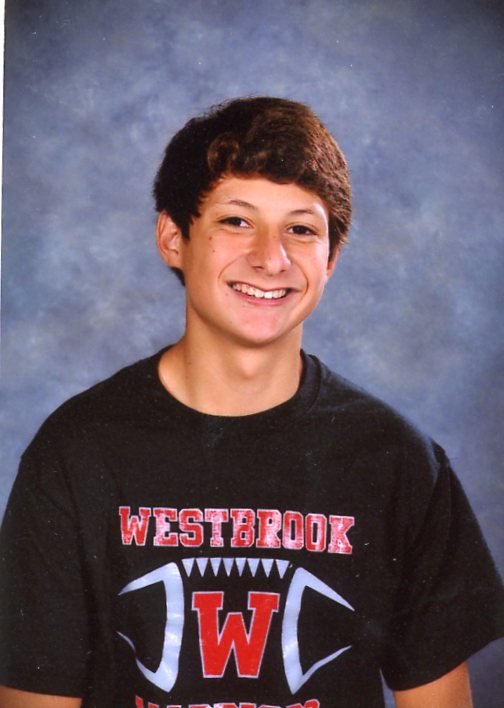 Gilbert as a teenager, smiling in a dark shirt for a school portrait.