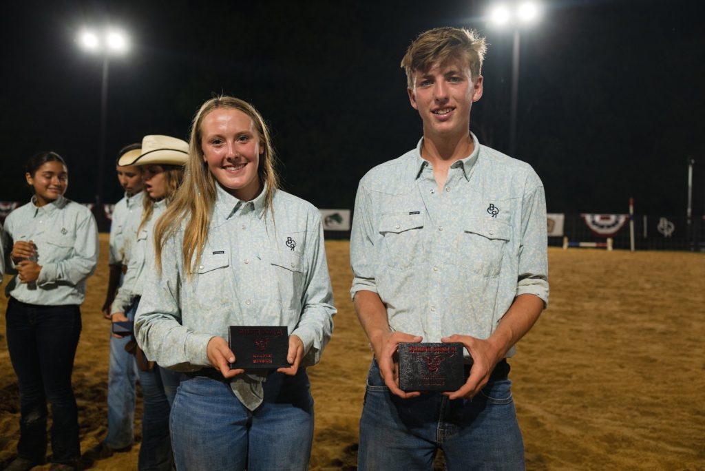 Makenzie and Nathan, this year's Head Wranglers, smile side by side in the arena at night.